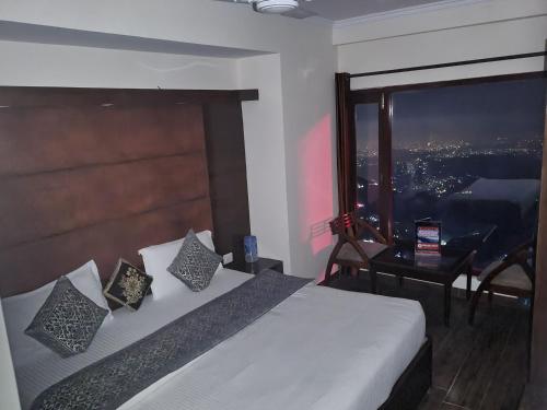 a bedroom with a bed with a large window at Hotel MountMemory , Barkot-Yamunotri in Barkot