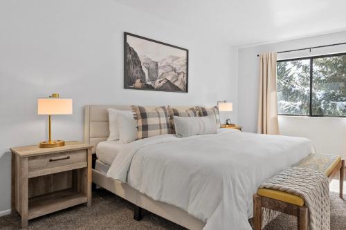 a white bedroom with a bed and a window at Cozy Top Floor Condo with Mountain Views in Park City