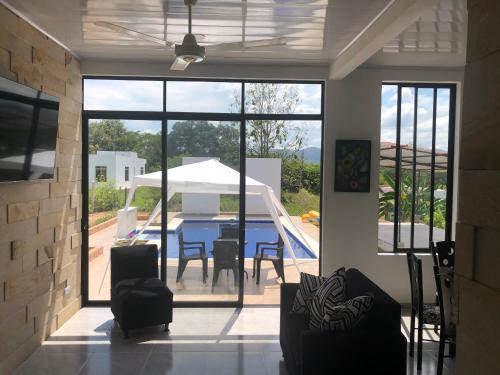 a living room with a table and chairs and a pool at Villa con piscina privada y zona bbq en condominio in Carmen de Apicalá