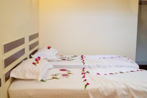 two white beds with flowers on them at Relax Villa in Thoddoo