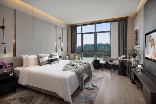 een slaapkamer met een groot bed en een groot raam bij Somerset Southbay Zhuhai-Hengqin Port in Zhuhai