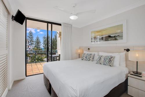 a white bedroom with a bed and a balcony at Calypso Plaza Resort Unit 429 in Gold Coast