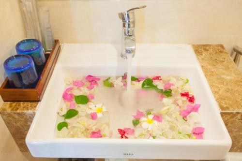 een witte wastafel met bloemen in het water bij Ecstasy Hotel in Nha Trang