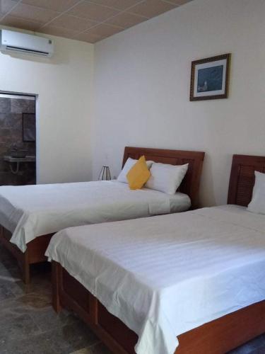 two beds in a room with white walls at The Natural Bungalow in Hoi An