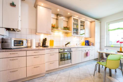 a kitchen with white cabinets and a table at Ferienwohnung Köln Messenähe in Cologne