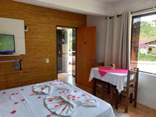 a room with two beds and a table and a television at Estalagem Brumone in Monte Verde