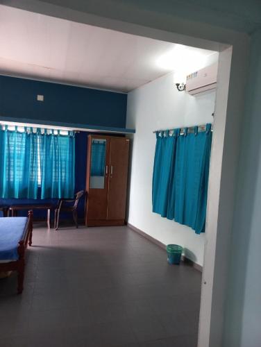 a room with blue curtains and a room with a bed at Sun n Tan Beach Home stay in Kannur