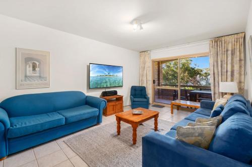 a living room with two blue couches and a table at Radburn Ondine Close 3 17 in Nelson Bay
