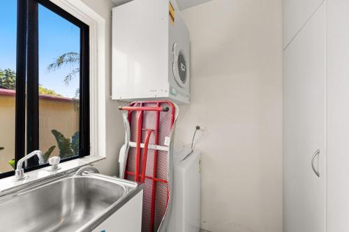 a kitchen with a sink and a red fire extinguisher at Radburn Ondine Close 3 17 in Nelson Bay