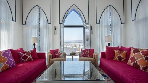 a living room with red couches and a table at Cloud 7 Residences Ayla Aqaba in Aqaba