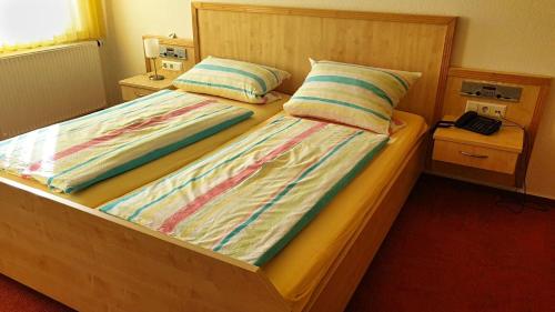 ein Schlafzimmer mit einem Bett mit zwei Kissen und einem Telefon in der Unterkunft Gasthaus Linde in Ingelfingen