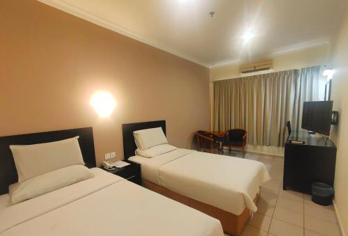 um quarto de hotel com duas camas e uma televisão em Megah D'aru Hotel em Kota Kinabalu