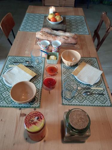 einem Holztisch mit Teller und Schüsseln aus Essen in der Unterkunft Chambre d'hôtes Le Cocon des Champs in Buzet-sur-Baïse