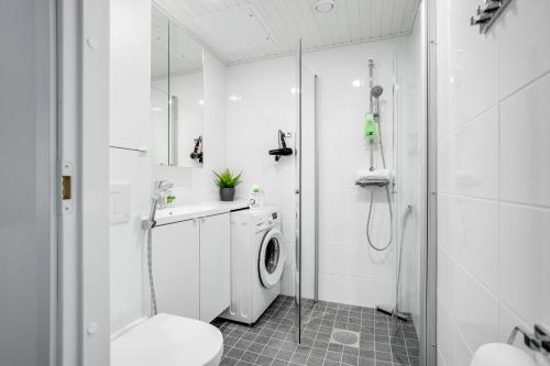 a white bathroom with a washing machine and a shower at Hiisi Homes Nokia Nansonkatu in Nokia