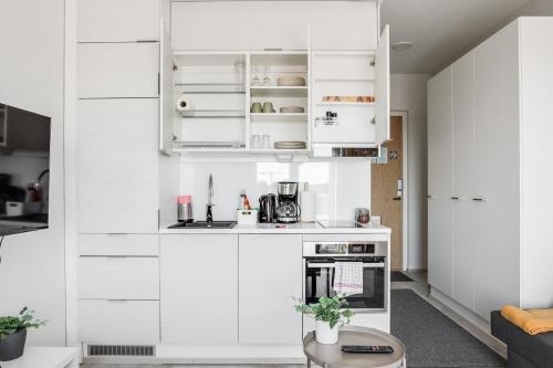 a white kitchen with white cabinets and a table at Hiisi Homes Nokia Nansonkatu in Nokia
