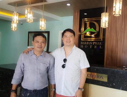 two men standing next to each other in a restaurant at Dalian Peak Hotel in Angeles
