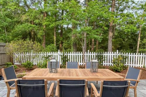a wooden table with chairs and a white fence at Falling Moss in Porcher Bluff