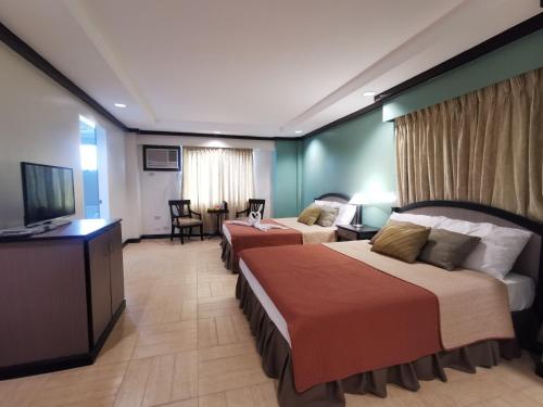 a hotel room with two beds and a flat screen tv at Tagaytay Country Hotel in Tagaytay