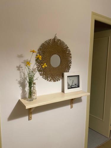 a mirror on a wall with a shelf with flowers at Piso en la costa brava y al inicio del Pirineo in Portbou
