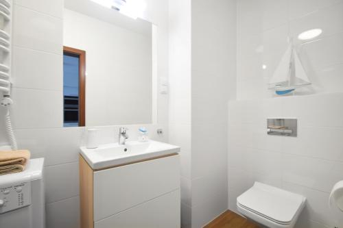 ein weißes Bad mit einem Waschbecken und einem WC in der Unterkunft DWIE SOSNY Baltic 35 in Ustronie Morskie