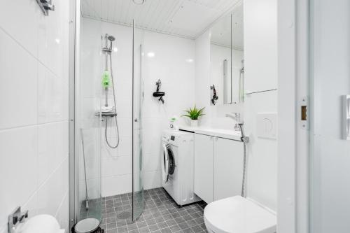 a bathroom with a shower sink and a washing machine at Hiisi Homes Nokia Nansonkatu in Nokia