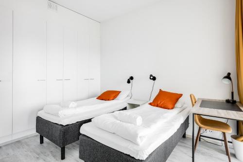 two beds in a room with a table and chairs at Hiisi Homes Nokia Nansonkatu in Nokia