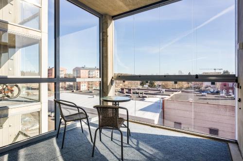 a balcony with two chairs and a table and some windows at Hiisi Homes Nokia Nansonkatu in Nokia