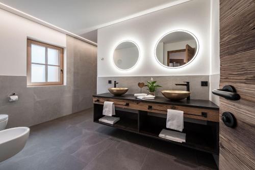 a bathroom with two sinks and two mirrors at Mein Sonnenhof in San Valentino alla Muta