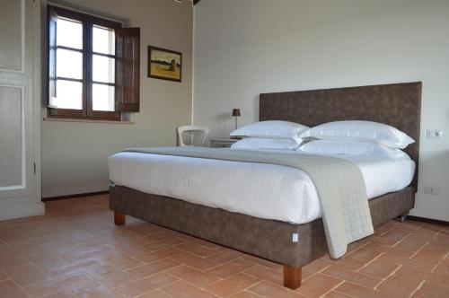una camera da letto con un grande letto con lenzuola e cuscini bianchi di Opera Domini Asisium a Torchiagina