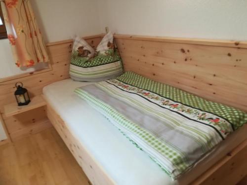 a small bedroom with a wooden bed with two pillows at Ferienwohnung Familie Fiechtl in Fügenberg
