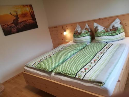 a bed with green sheets and pillows on it at Ferienwohnung Familie Fiechtl in Fügenberg