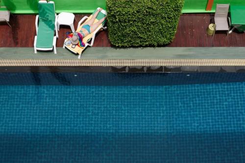 a pool with a person laying in a lounge chair next to a pool at Stay Resort Pattaya in North Pattaya