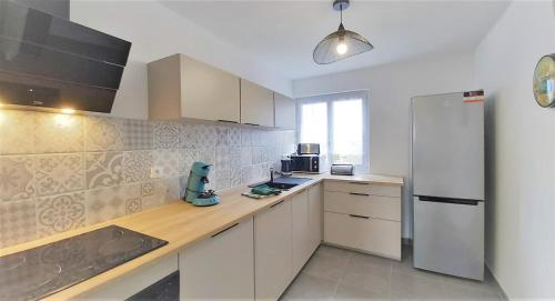 une cuisine avec des armoires blanches et un réfrigérateur blanc dans l'établissement Groix, à Lorient