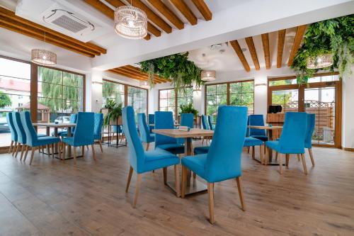 a dining room with blue chairs and tables at Villa Astra - Apartments & Restaurant in Oświęcim