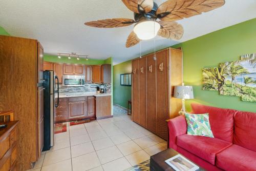 a living room with a red couch and a ceiling fan at OUTSTANDING OCEANFRONT STUDIO - KONA ISLANDER INN CONDOS condo in Kailua-Kona