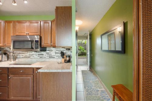 a kitchen with wooden cabinets and green walls at OUTSTANDING OCEANFRONT STUDIO - KONA ISLANDER INN CONDOS condo in Kailua-Kona