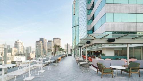 un balcón con mesas y sillas y un edificio en Ascott Huai Hai Road Shanghai, Xintiandi en Shanghái
