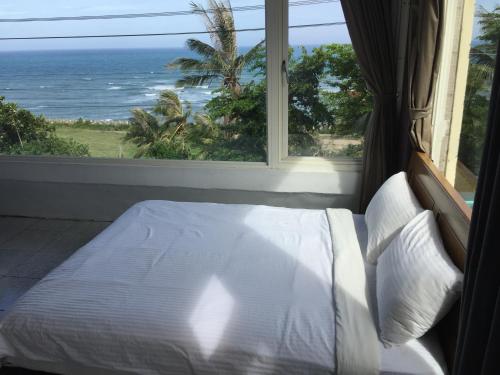 a bedroom with a bed with a view of the ocean at Donghe surf shop & Hostel in Donghe