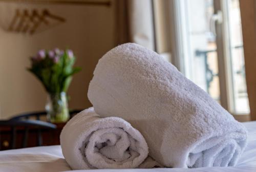 un rouleau de serviettes blanches posé sur un lit dans l'établissement Les Nids Perchés - Rue Sainte Croix, à Mortagne-au-Perche