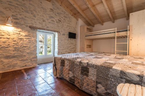 LE MOULIN DU VIVIER في Saint-Martin-Lalande: غرفة نوم بسرير في غرفة بجدار من الطوب