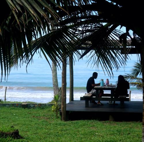 two people sitting at a picnic table near the beach at Afro Beach eco Resort Butre in Butre