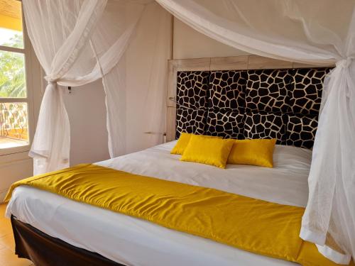 a bedroom with a bed with yellow pillows at Le Souimanga Hotel Saly in Saly Portudal