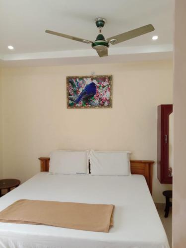 a bedroom with a white bed with a ceiling fan at Shubhanga Residency in Srikalahasti