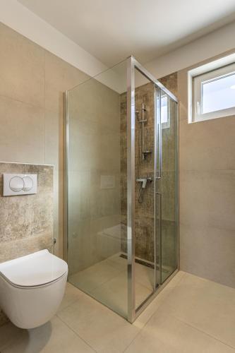 a bathroom with a glass shower and a toilet at Sunset Apartment in Cres