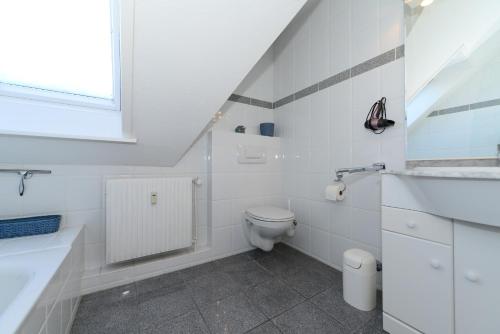 een witte badkamer met een toilet en een wastafel bij Haus Albatros Whg 04 in Wyk auf Föhr