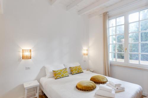 a white bedroom with a bed and a window at Maison d'Orange - La Pinede in Saint-Tropez