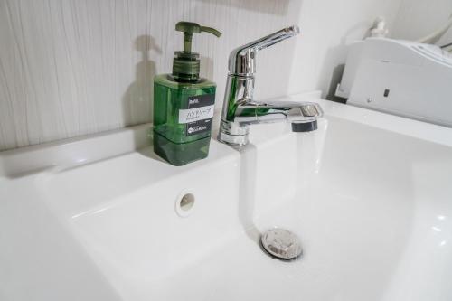 a green bottle of soap sitting on a bathroom sink at HANASTAY花渓居 · 海（UMI) in Osaka