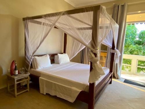 a bedroom with a canopy bed and a window at Paje Beach Apartments & Hotel in Paje