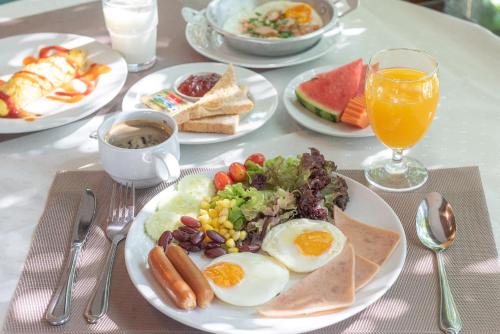 a table topped with plates of breakfast foods and drinks at Nonthaburi Palace Hotel in Nonthaburi