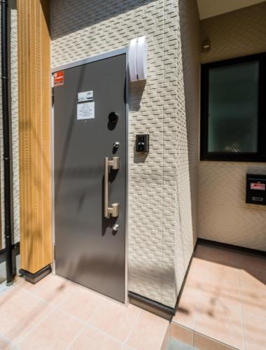 a metal door in a room with a brick wall at HANASTAY花渓居 · 海（UMI) in Osaka